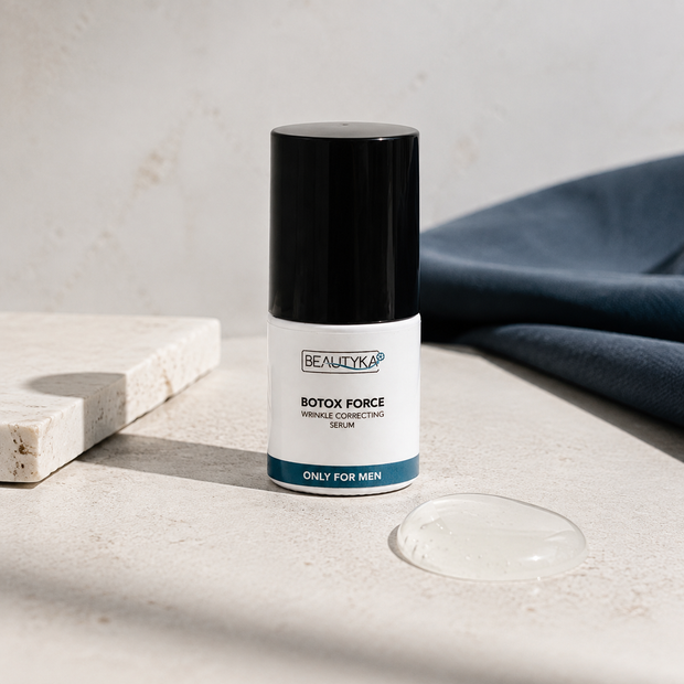 Beautyka Botox Force Wrinkle Correcting Serum bottle on a textured beige stone surface with a marble tile, a clear gel droplet, and a navy blue fabric background.