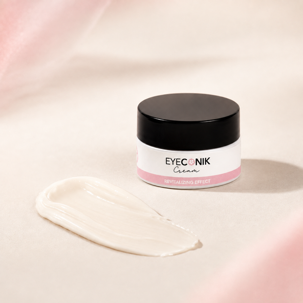 Beautyka Eyeconik Eye Cream jar on a soft beige surface with a smear of white cream in front.
