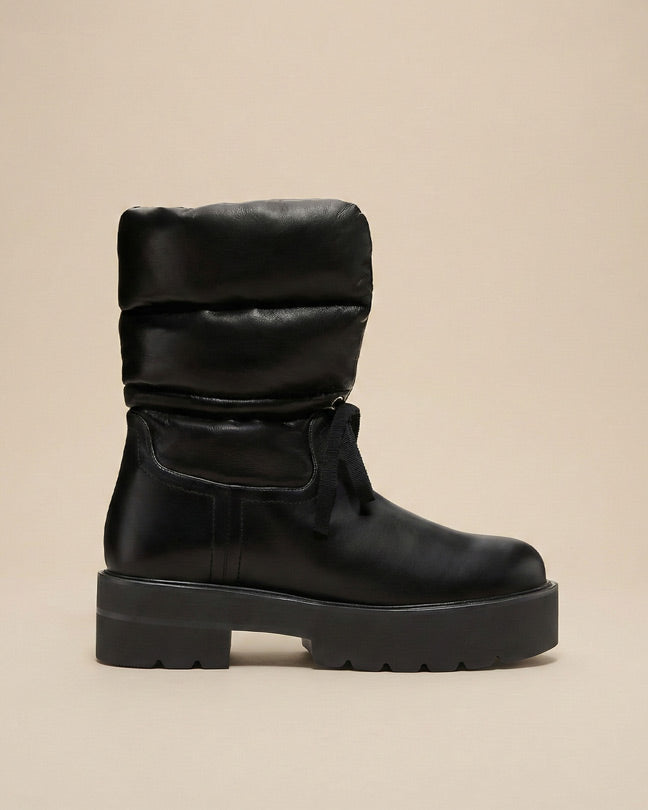 Black puffer winter boot with chunky sole and round toe on beige background