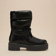 Black puffer winter boot with chunky sole and round toe on beige background
