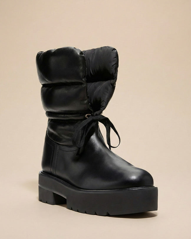 Black winter boot with chunky sole, padded shaft, and round toe on a neutral background