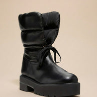 Black winter boot with chunky sole, padded shaft, and round toe on a neutral background
