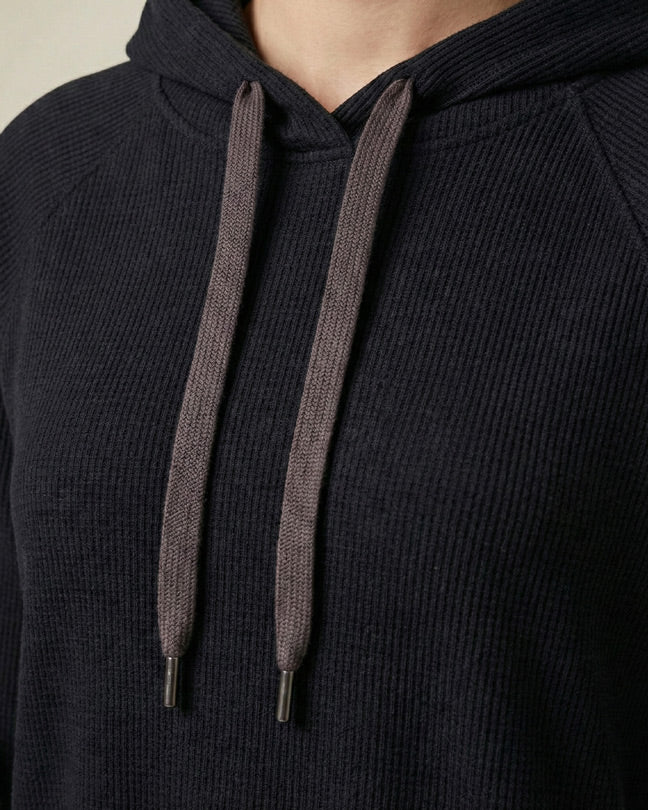 Close-up of a black ribbed hoodie with gray drawstrings and metal tips