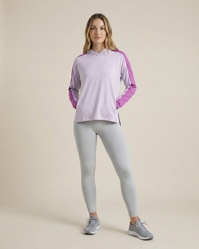 Woman in lilac athletic hoodie with purple stripes and grey leggings, standing indoors