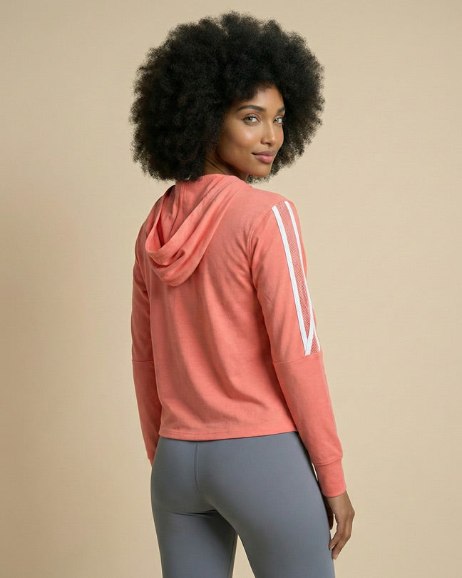 Woman in coral pink hooded sweatshirt with white stripes and gray leggings, back view