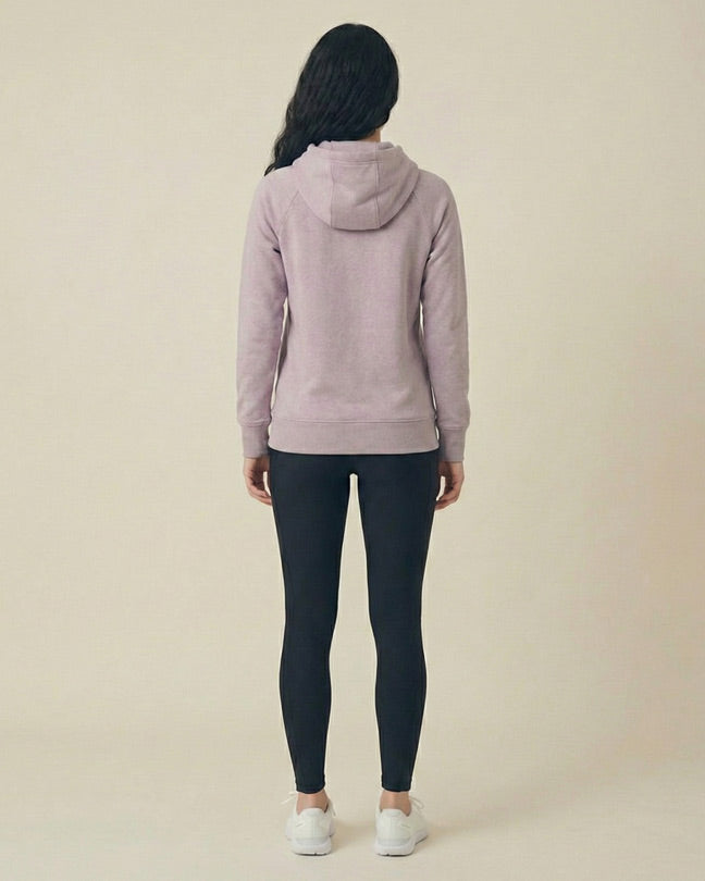 Woman in lavender hoodie and black leggings standing, viewed from the back, on neutral background