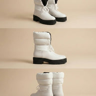 Chunky white winter boots with thick black soles and padded uppers on neutral background