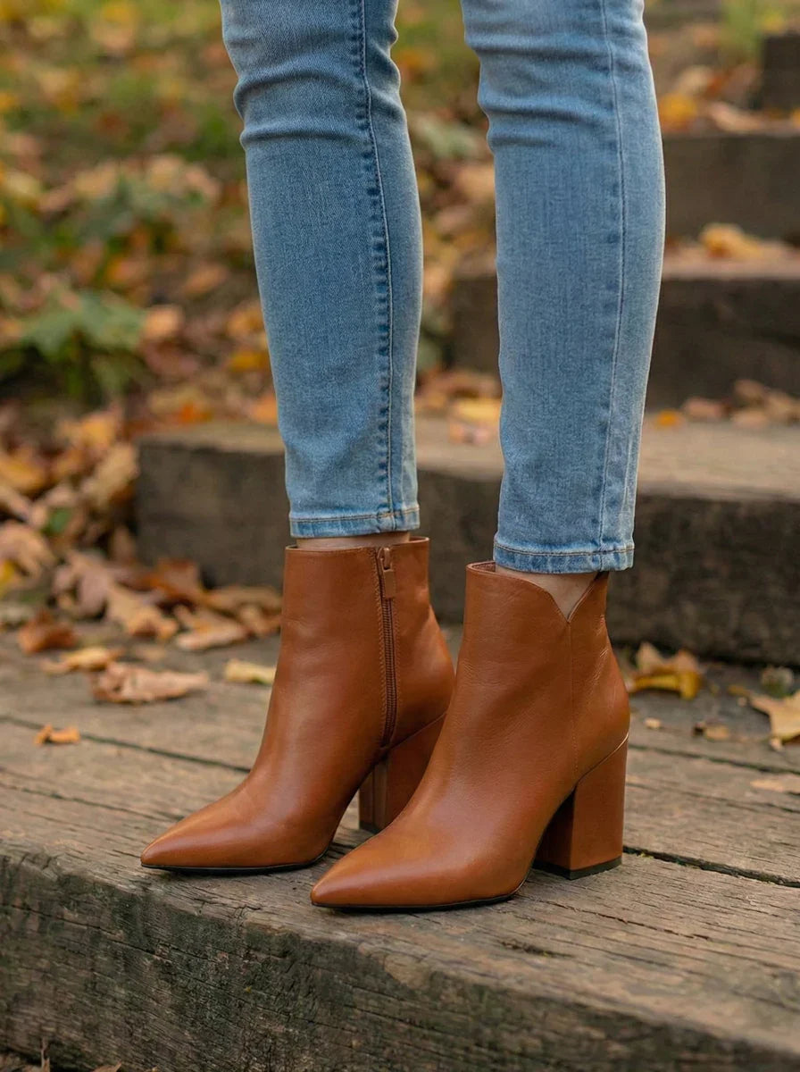 Brown leather ankle boots with block heels worn with skinny jeans outdoors on wooden steps