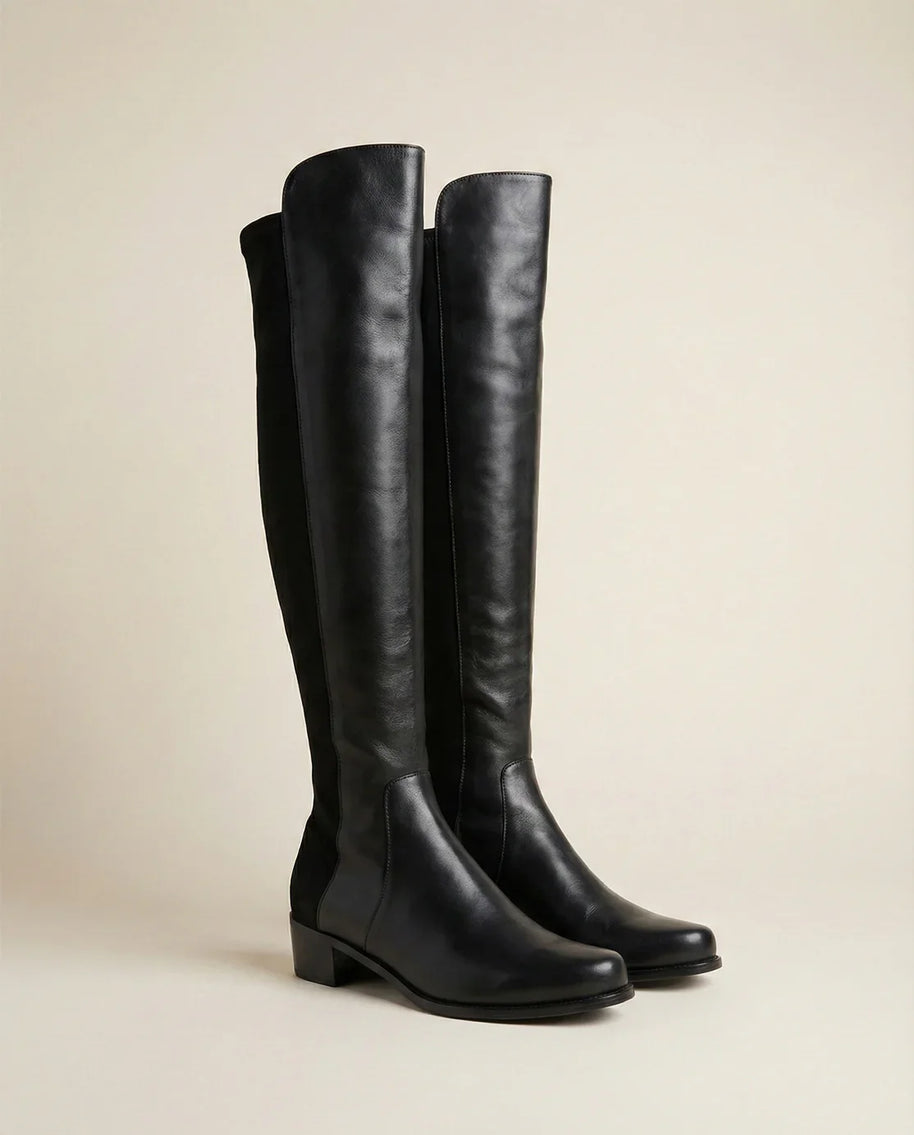Black knee-high leather boots with low block heel on neutral background