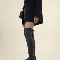 Woman wearing black blazer, mini skirt, and over-the-knee black leather boots