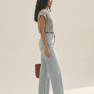 Woman modeling casual striped shirt, light blue wide-leg jeans, brown shoes, and woven bag