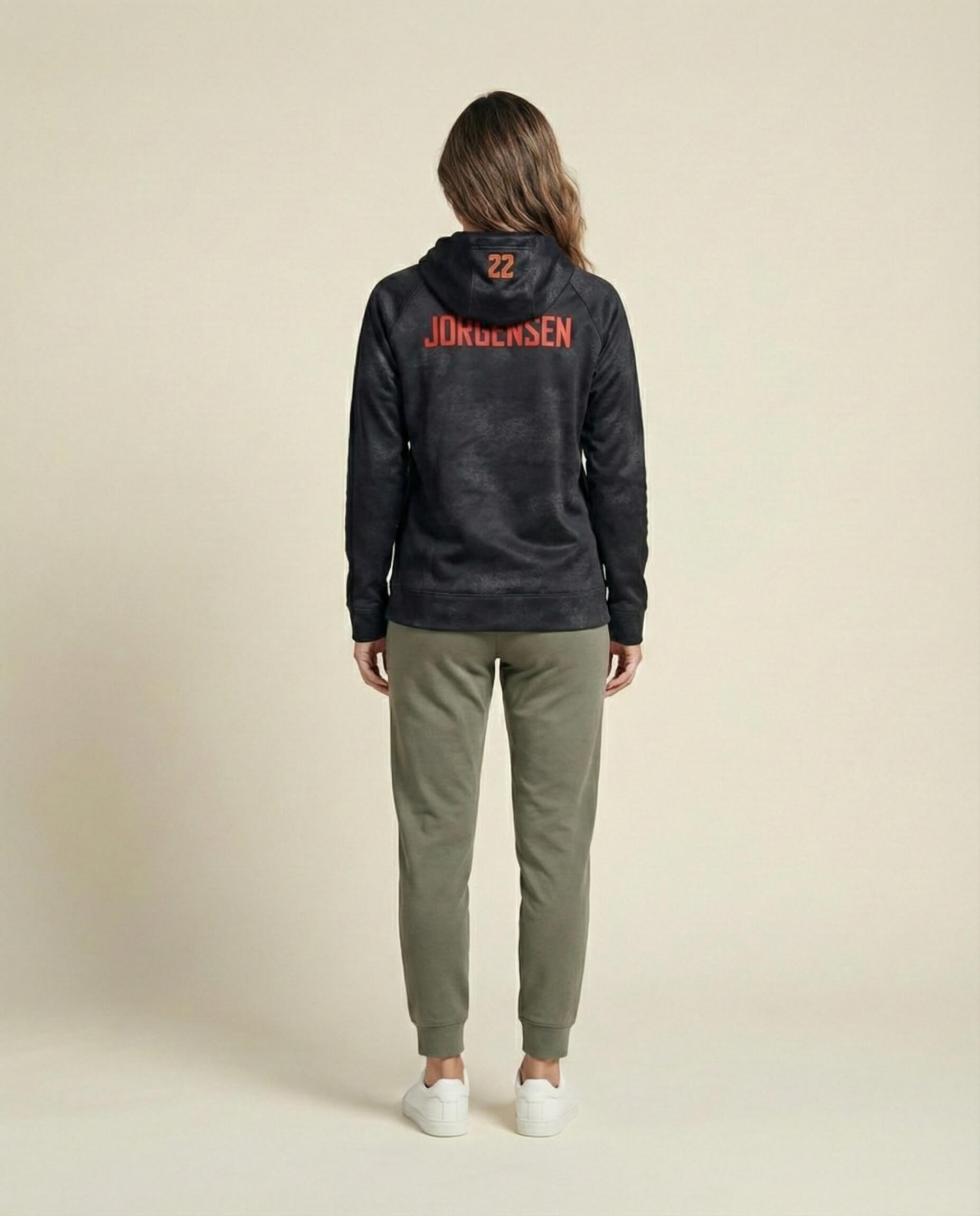 Woman modeling black hoodie with red lettering and olive jogger pants, rear view