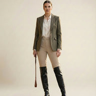Woman in equestrian outfit with tweed blazer, beige riding pants, and tall black boots