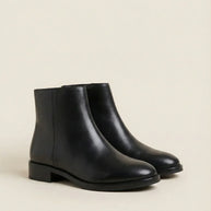 Black leather ankle boots with low stacked heels on a neutral background