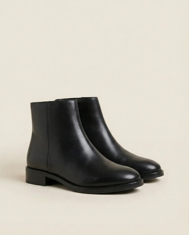 Black leather ankle boots with low stacked heels on a neutral background