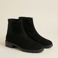Black suede ankle boots with chunky soles on a neutral background