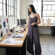Fashion designer in studio reviewing fabric samples and sketches on a desk
