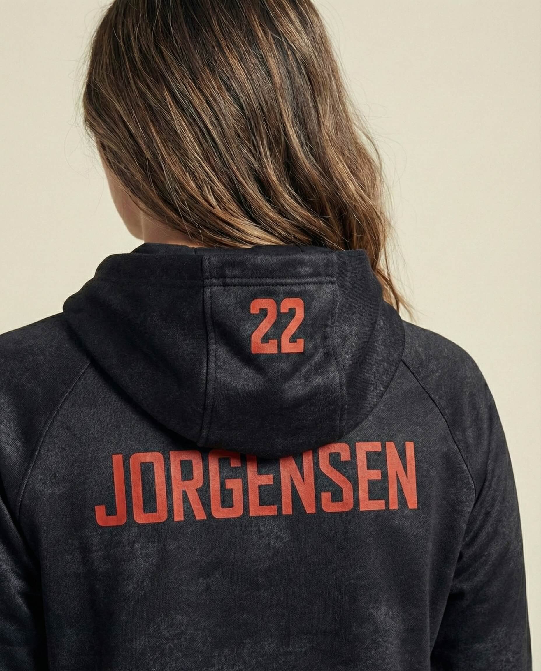 Back view of black hoodie with red 'Jorgensen' text and number 22, worn by person