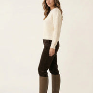 Woman in cream knit sweater, brown corduroy pants, and knee-high brown boots