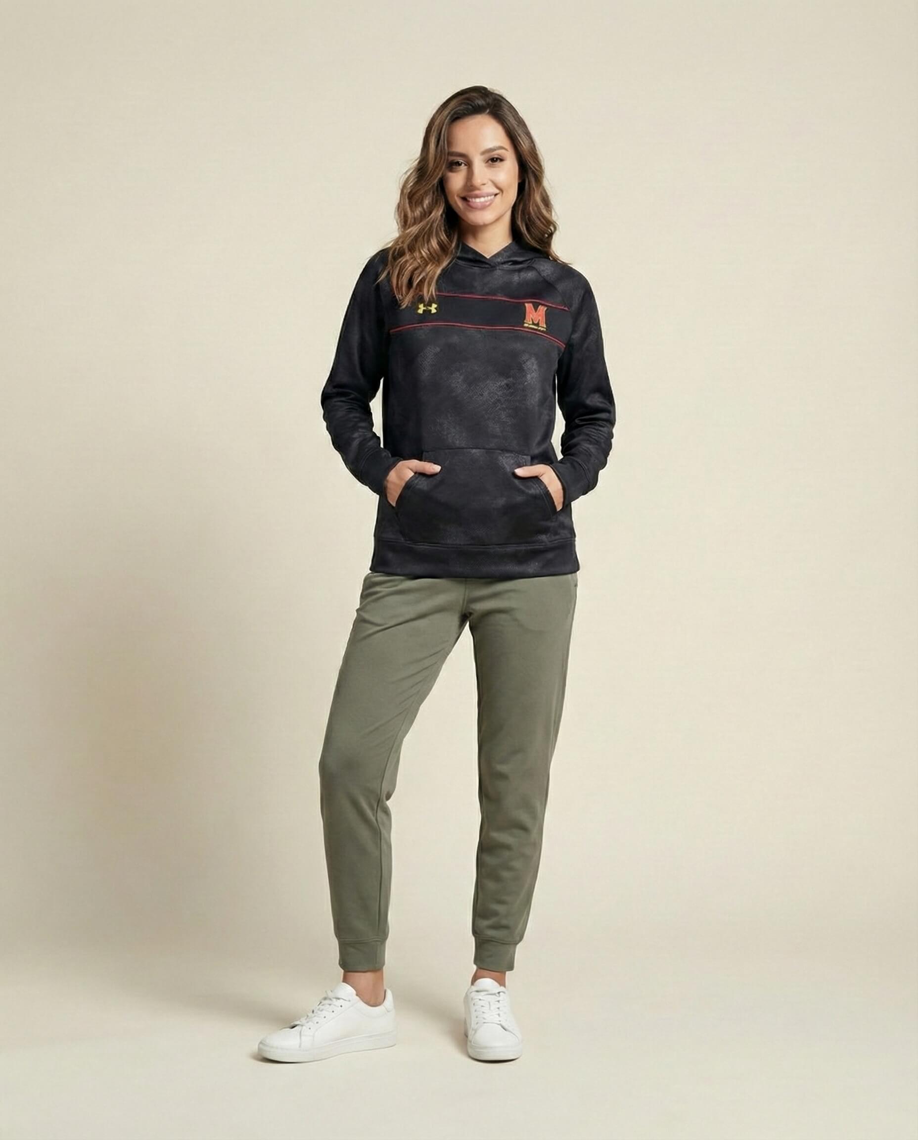 Woman wearing a black hoodie with red and yellow accents, olive joggers, and white sneakers