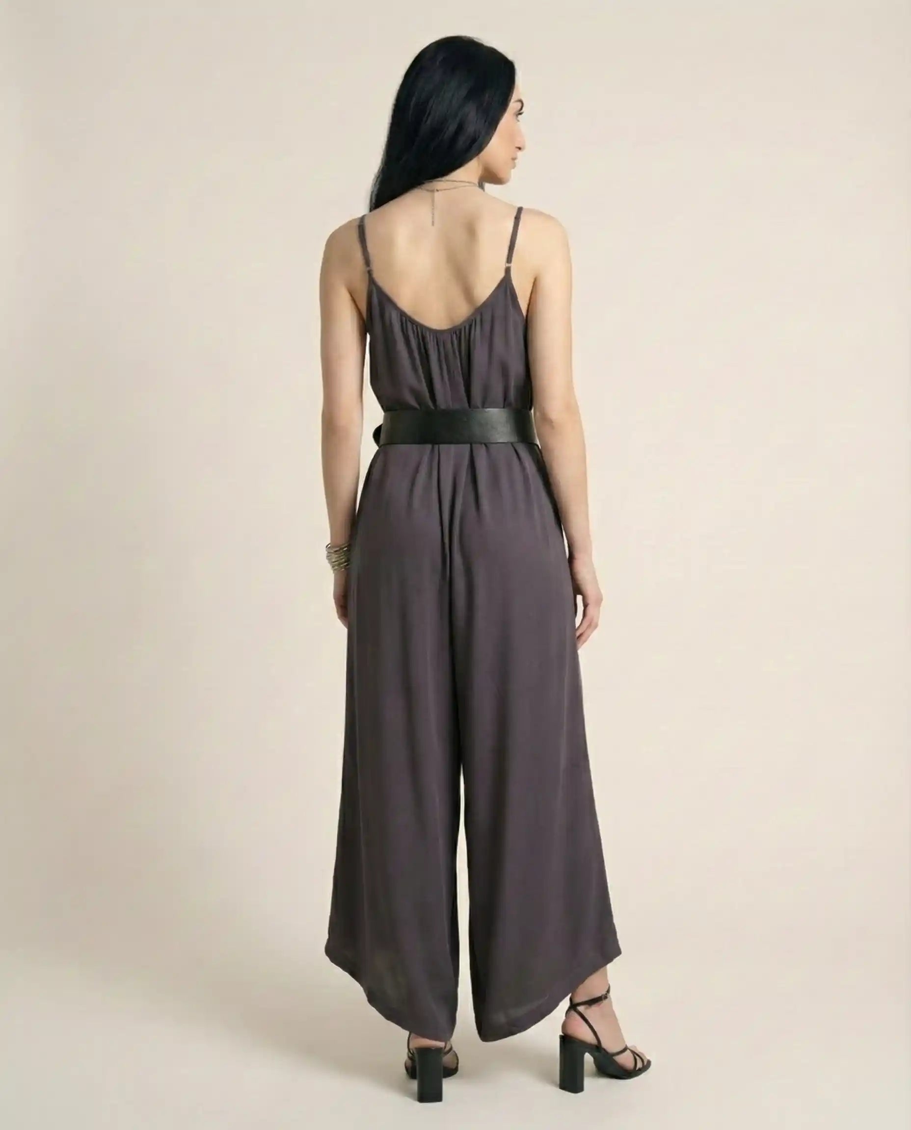 Woman wearing sleeveless wide-leg jumpsuit with black belt and heeled sandals, back view