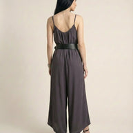 Woman wearing sleeveless wide-leg jumpsuit with black belt and heeled sandals, back view