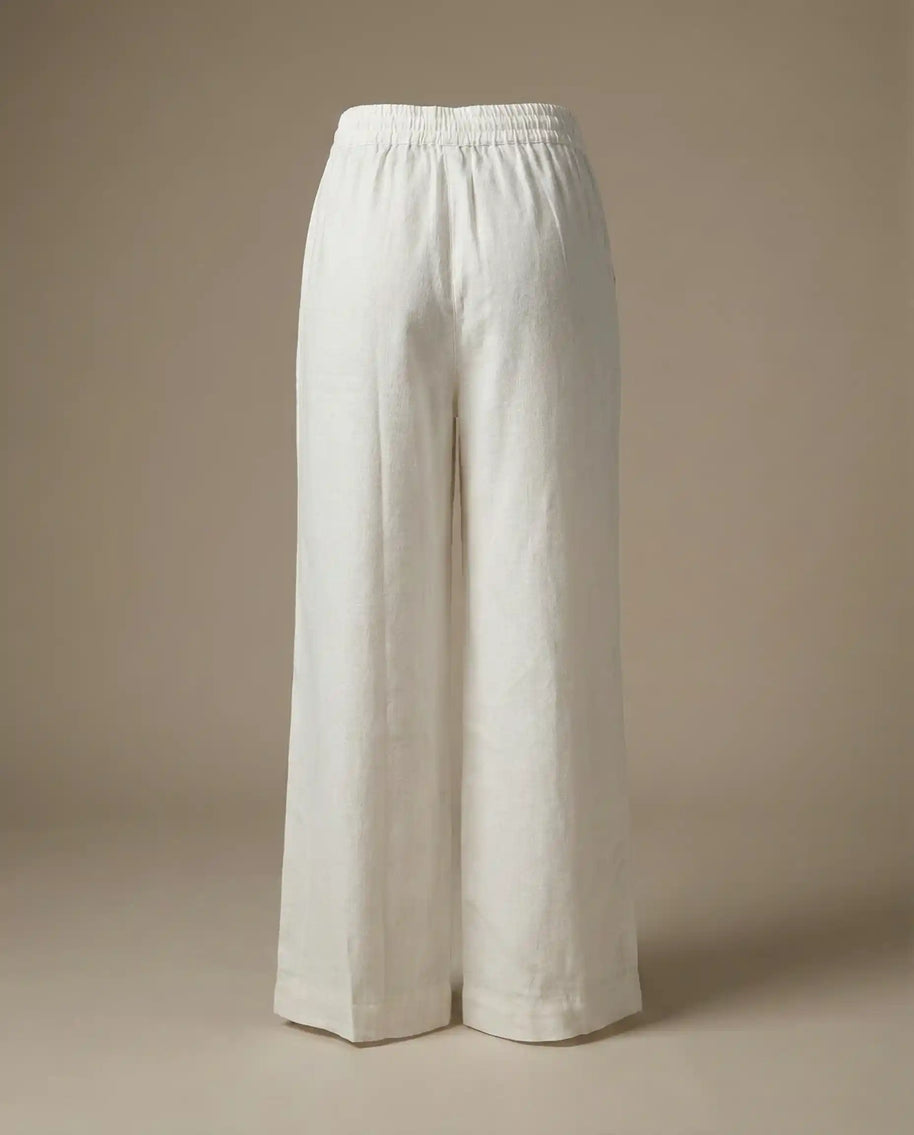 White wide-leg linen pants with elastic waistband on neutral background