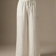 Wide leg white linen pants with elastic waistband and drawstring, neutral background