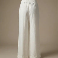 White wide-leg linen pants with elastic waistband on neutral background
