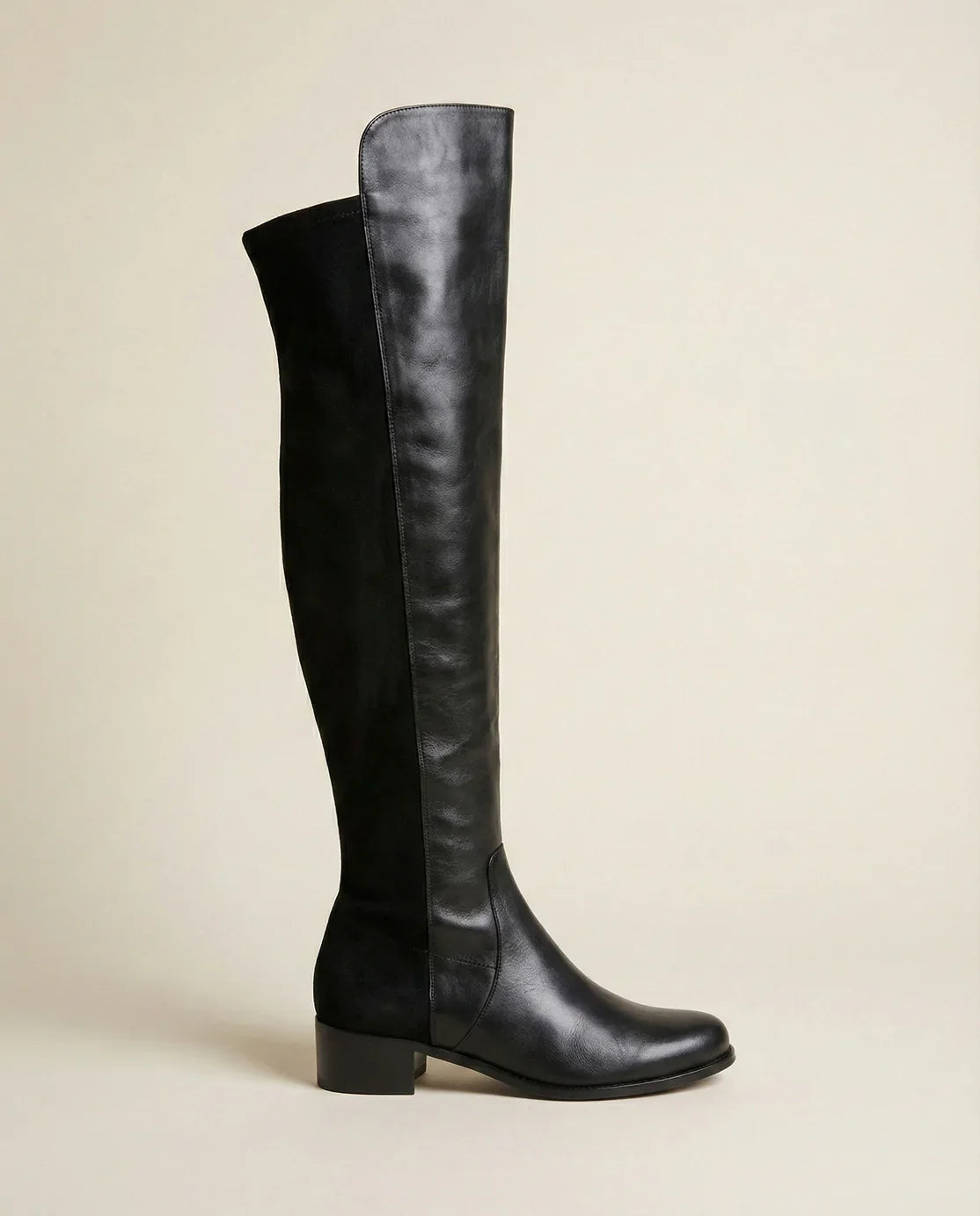 Black knee-high leather boot with low block heel on neutral background