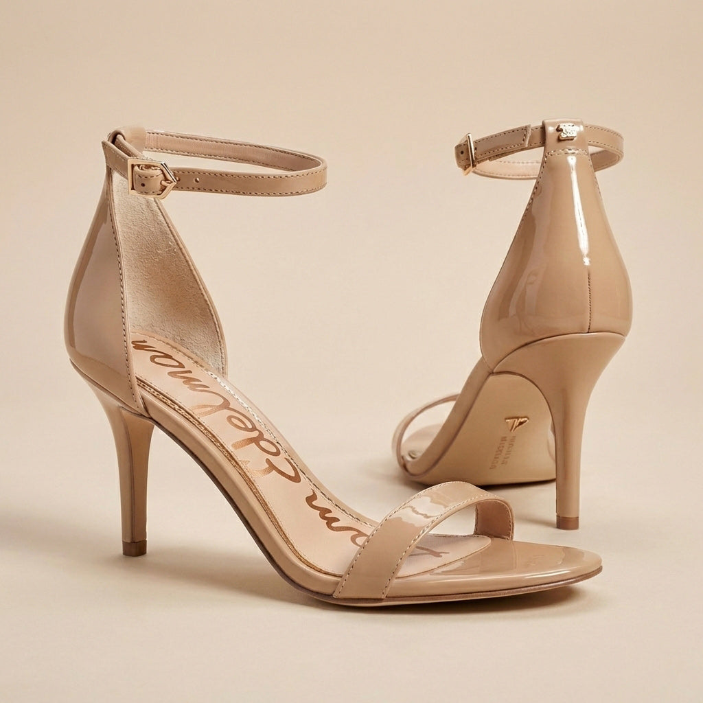 Beige patent leather high heel sandals with ankle straps on a neutral background.
