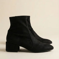 Pair of black suede ankle boots with block heels on a neutral background