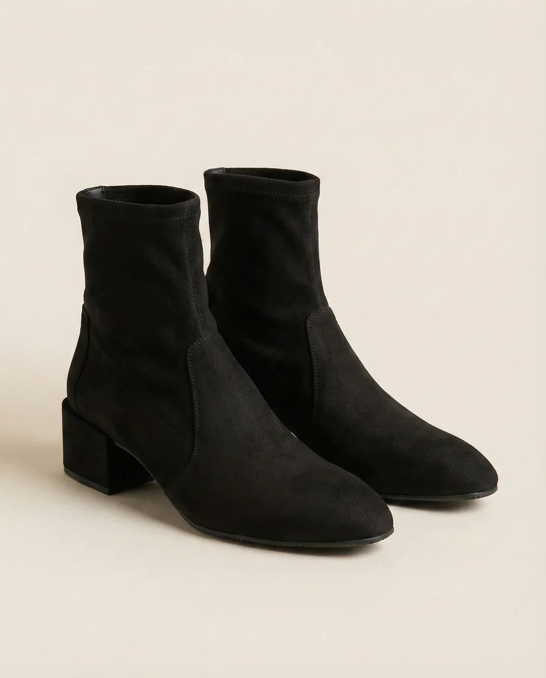 Black suede ankle boots with block heel on neutral background