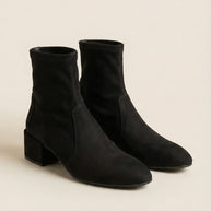 Black suede ankle boots with block heel on neutral background