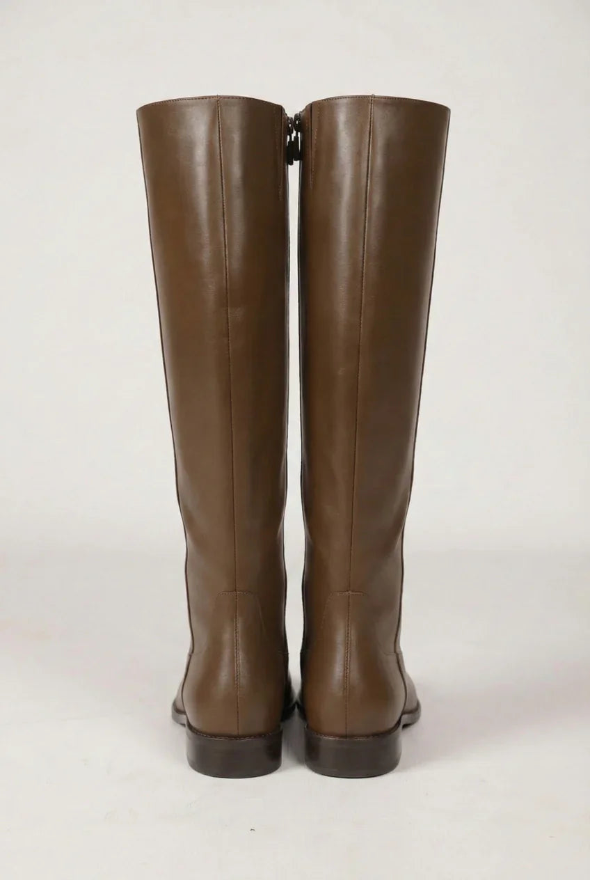 Pair of tall brown leather boots with low heels on a plain background