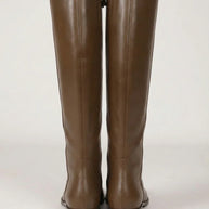 Pair of tall brown leather boots with low heels on a plain background