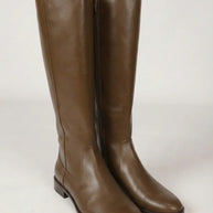Pair of tall brown leather knee-high boots with side zippers on a plain background
