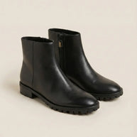 Black ankle boots with side zipper and chunky sole on neutral background