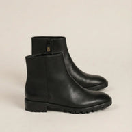 Black leather ankle boots with side zipper and lug sole on light background