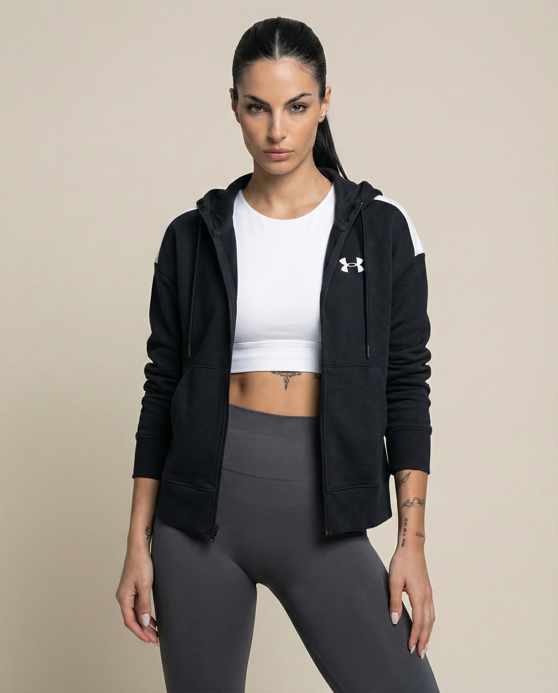 Woman wearing black zip hoodie, white crop top, and gray leggings, fitness apparel style