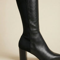 Black knee-high leather block heel boot on neutral background