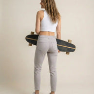 Woman in white crop top and light jeans holding skateboard, casual fashion style