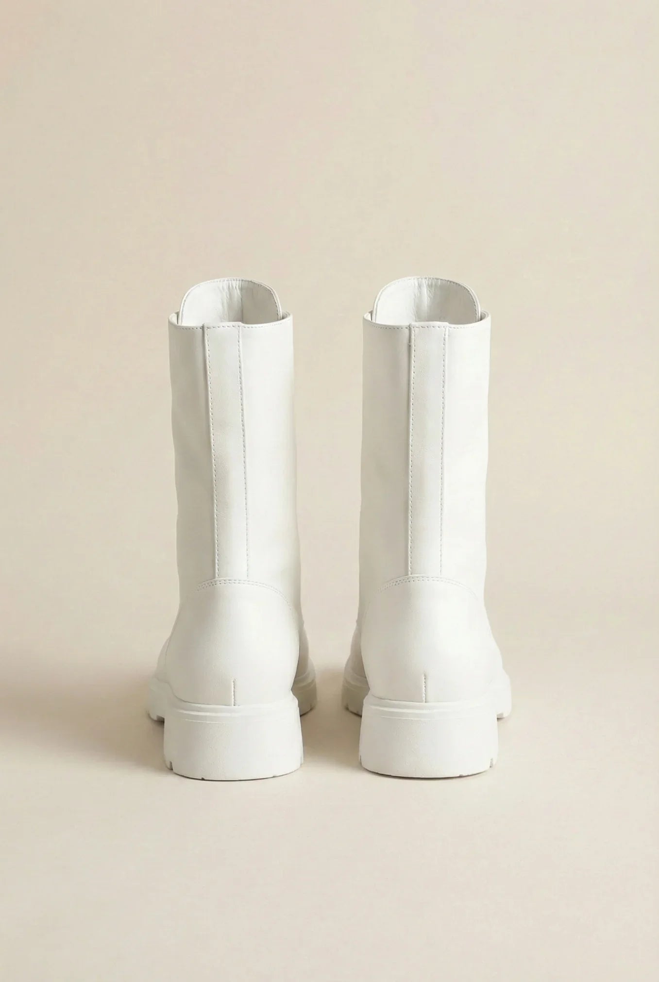 Pair of white mid-calf boots with chunky soles on a neutral background