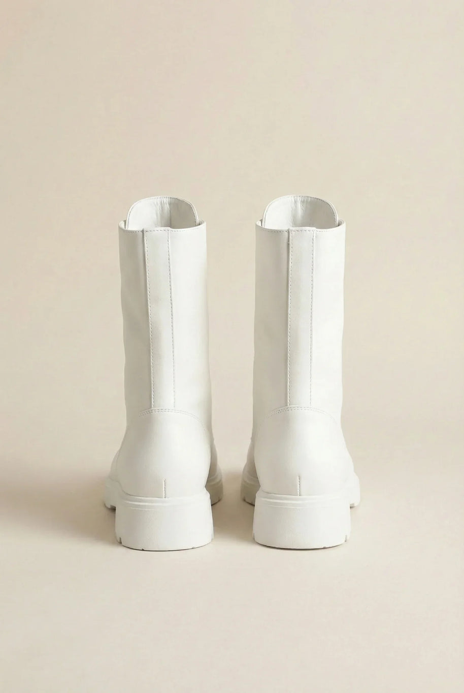 Pair of white mid-calf boots with chunky soles on a neutral background