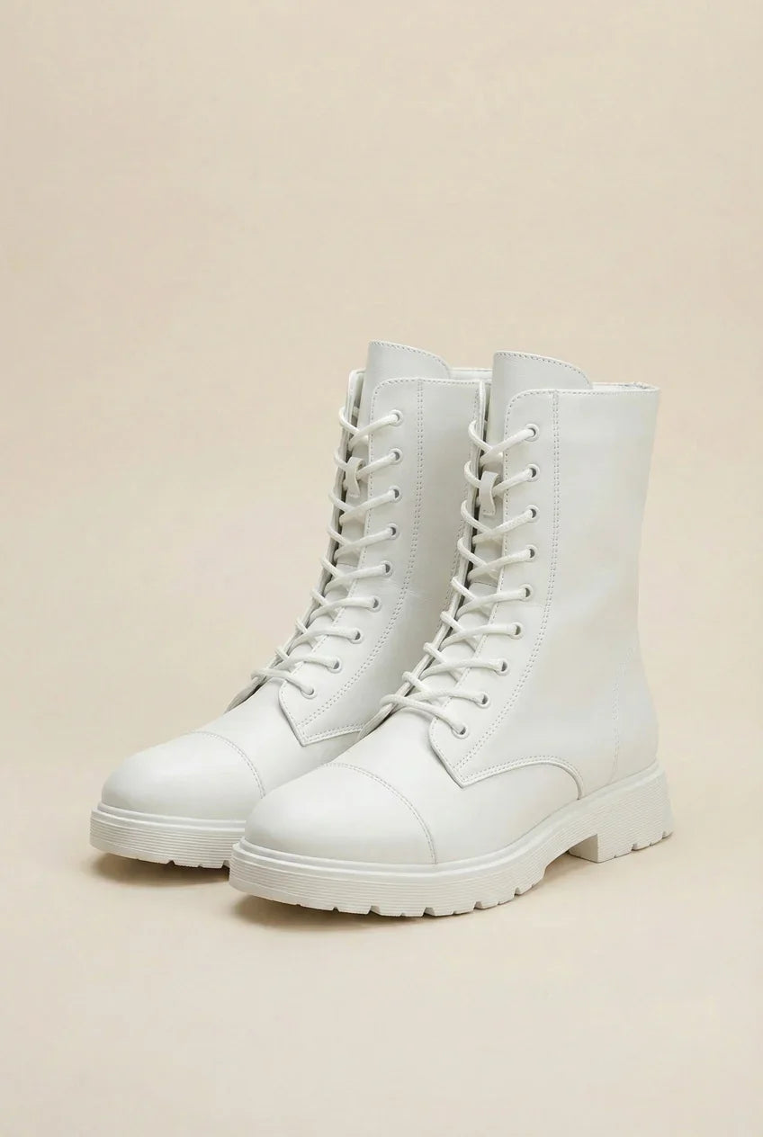 Pair of white lace-up combat boots with chunky soles on a neutral background
