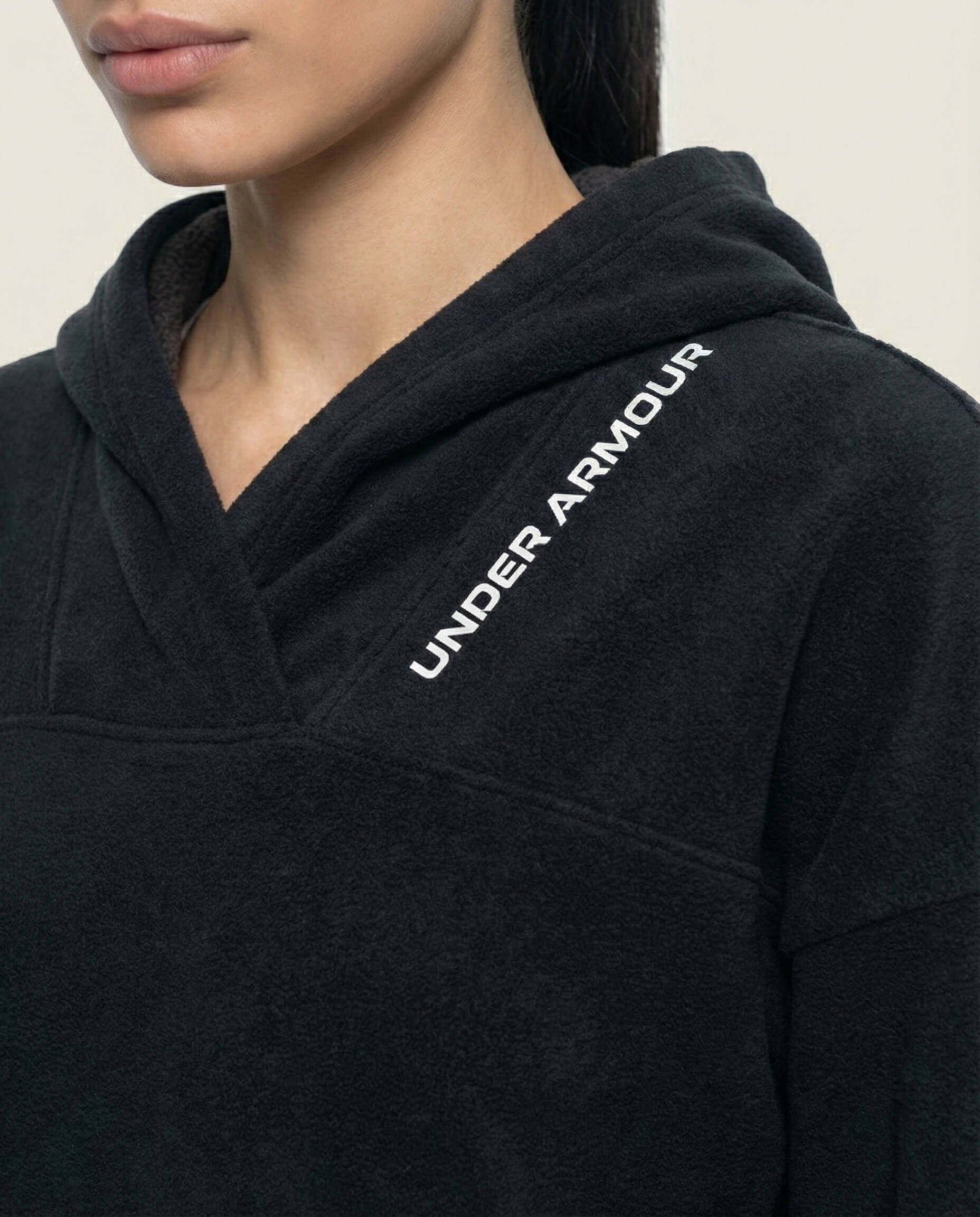 Woman wearing a black Under Armour fleece hoodie, close-up on logo and fabric texture