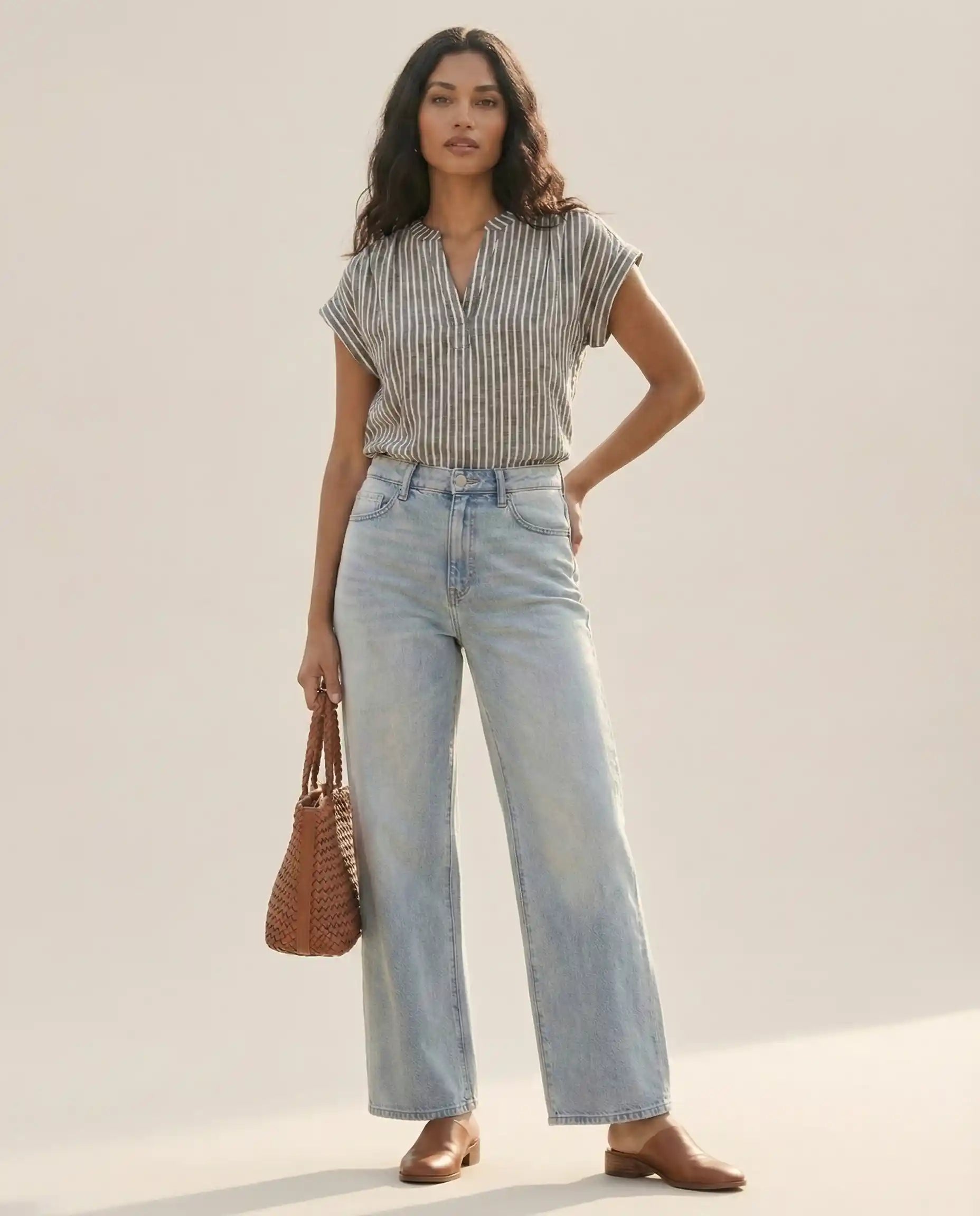 Woman in striped short-sleeve blouse and light-wash wide-leg jeans with brown woven bag