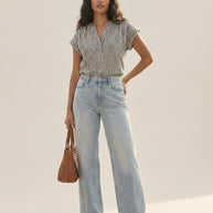 Woman in striped short-sleeve blouse and light-wash wide-leg jeans with brown woven bag