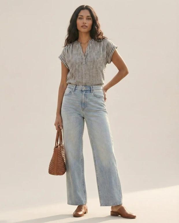 Woman in striped short-sleeve blouse and light-wash wide-leg jeans with brown woven bag