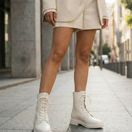 Woman wearing cream lace-up combat boots and matching shorts suit on city sidewalk